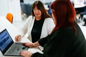 A female customer and female member of staff using a laptop.