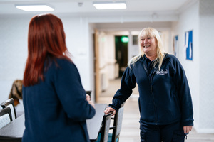 Two female Be One Homes colleagues talking to one another. They are wearing blue Be One Homes fleeces.