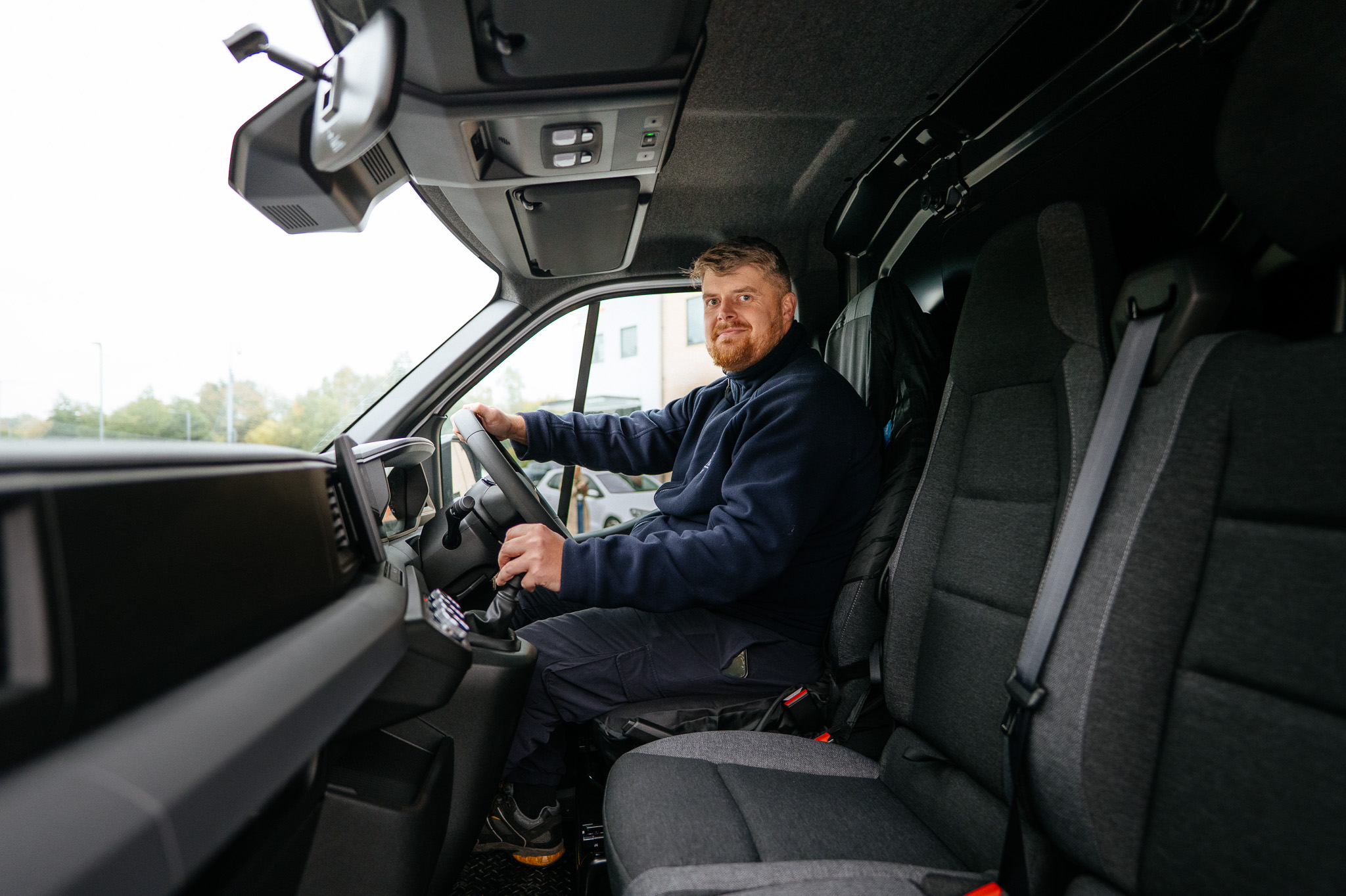 A male Be One Homes colleague driving one of our work vans. He is wearing a blue Be One Homes fleece.