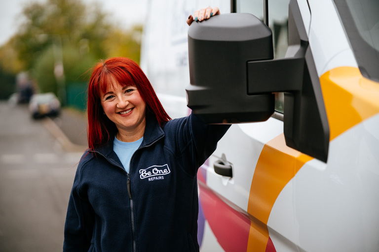 A female repairs colleague stood next to a Be One Repairs van.