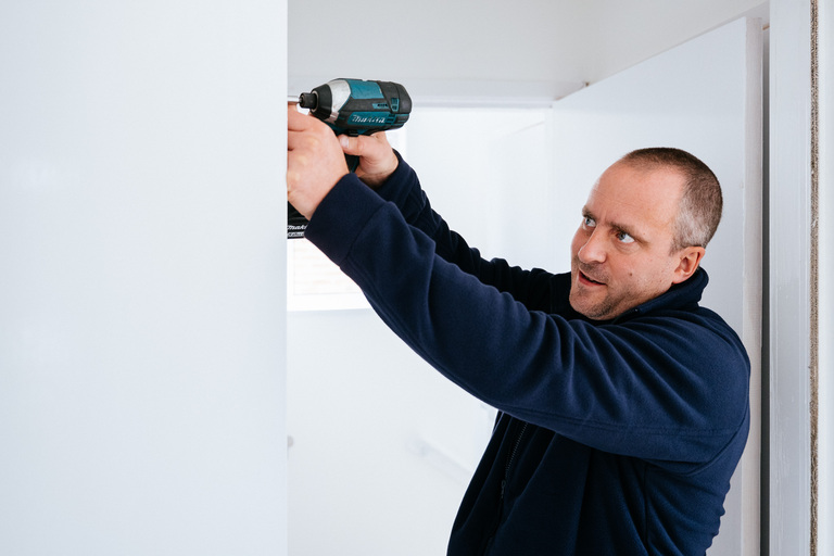 Male repairs operative using a drill.