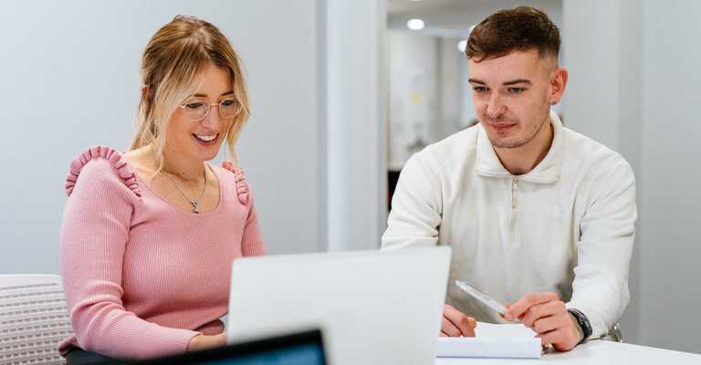 Two colleagues - female and male - work together on a laptop in our office.