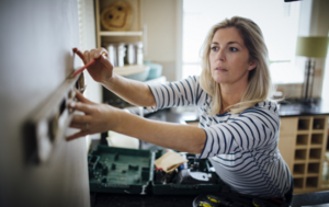A lady using a spirit level and pencil to mark a wall for alterations or decorating.